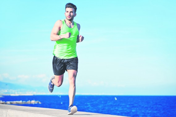 Attractive strong athlete running along the sea at evening